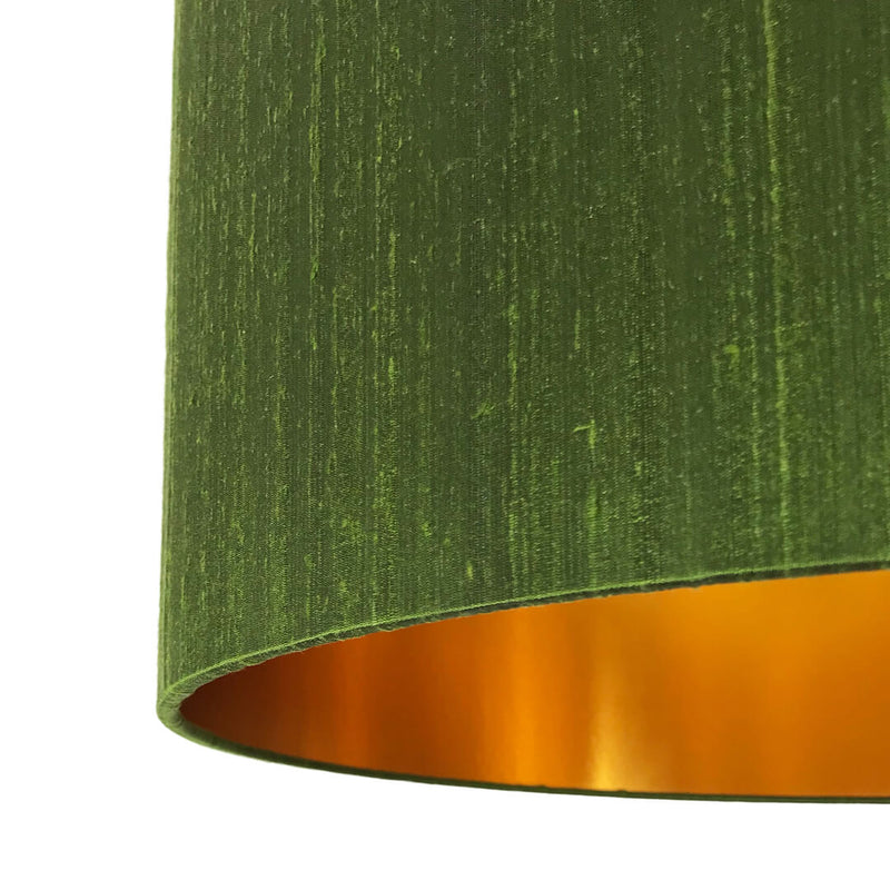 Close-up view of a moss green silk lampshade texture with gold lining, showcasing its intricate weave and luxurious feel