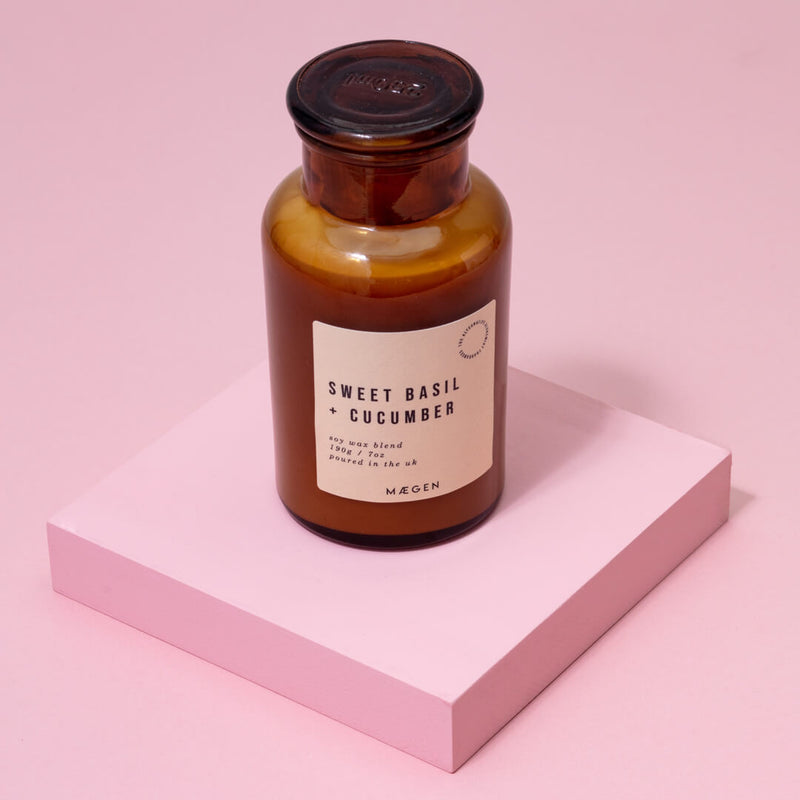 Lifestyle image of a 9oz scented apothecary glass candle with the scent of sweet basil and cucumber.